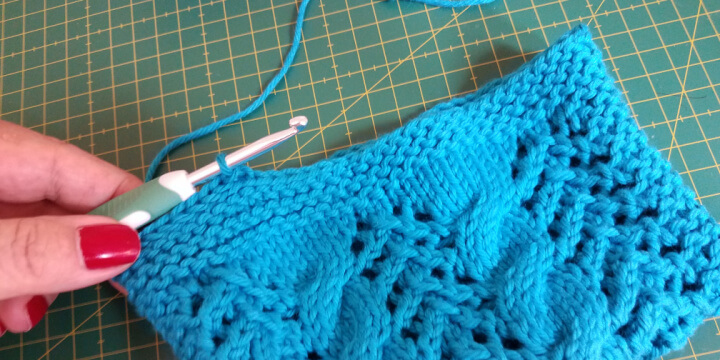 photo demonstrating how to slip stitch around the top of a knit clutch in order to reinforce the stitching