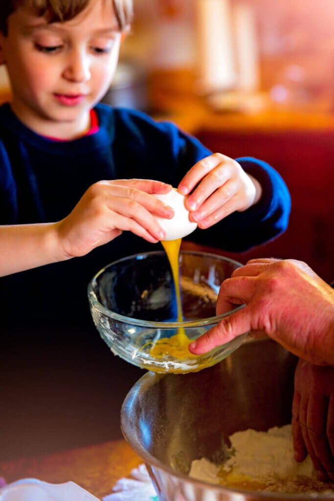 child breaking an egg into a bowl