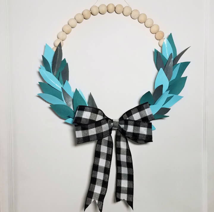 wooden bead wreath with leave and a buffalo plaid ribbon